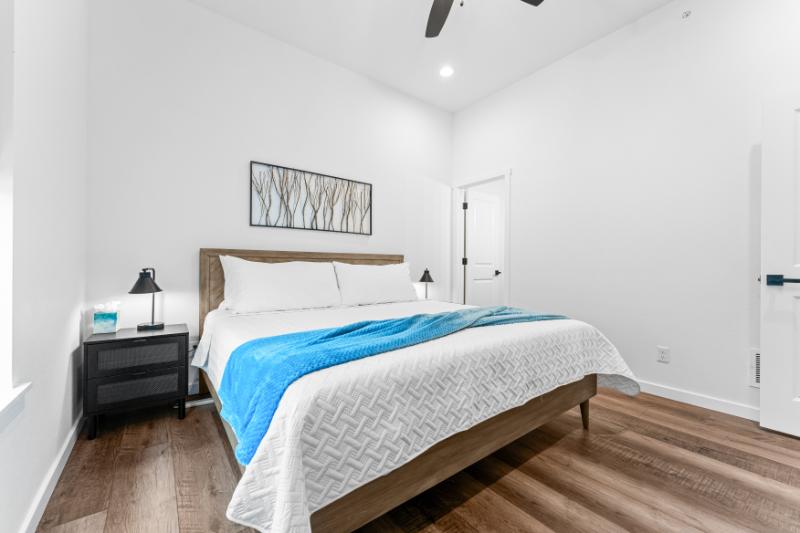 Unwind in this cozy king bedroom featuring plush bedding, wood floors, and calming décor.