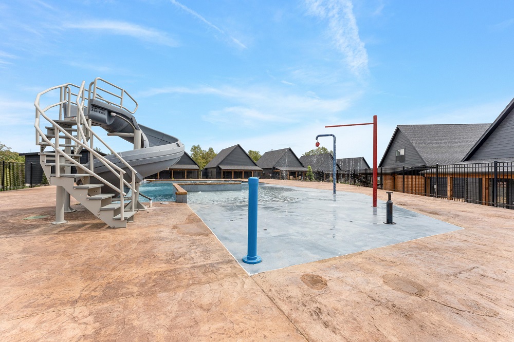 The outdoor pool includes a large slide and splash pad, providing fun for kids and adults alike.