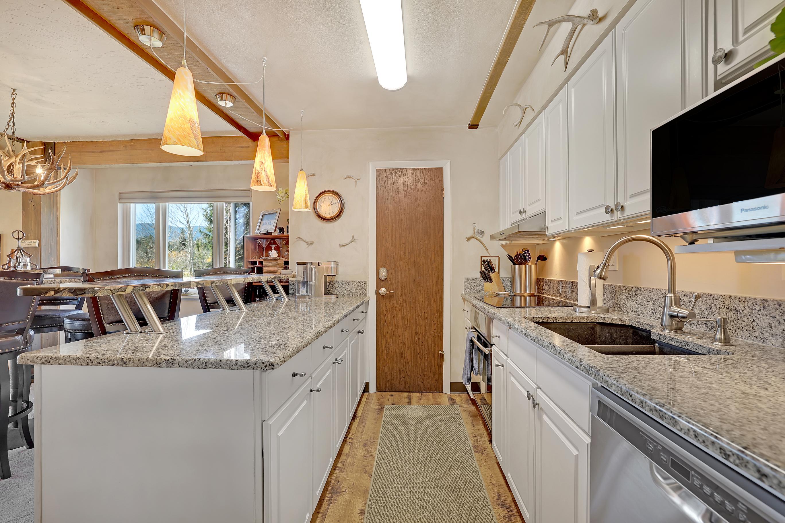 Modern, fully stocked kitchen with plates, glasses, and silverware plus large and small appliances.