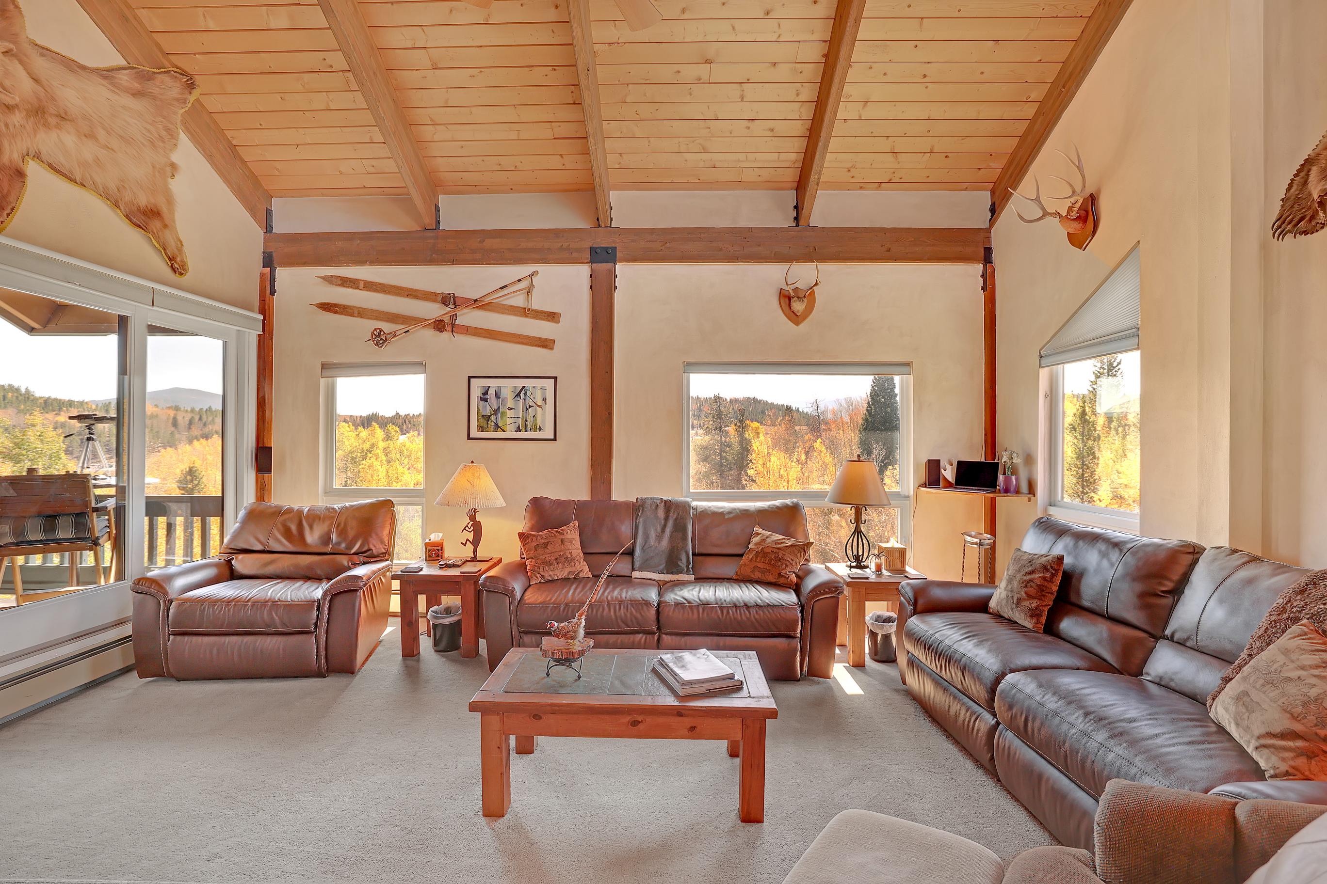 The living room has seating for all surrounded by mountain views and access to the private balcony