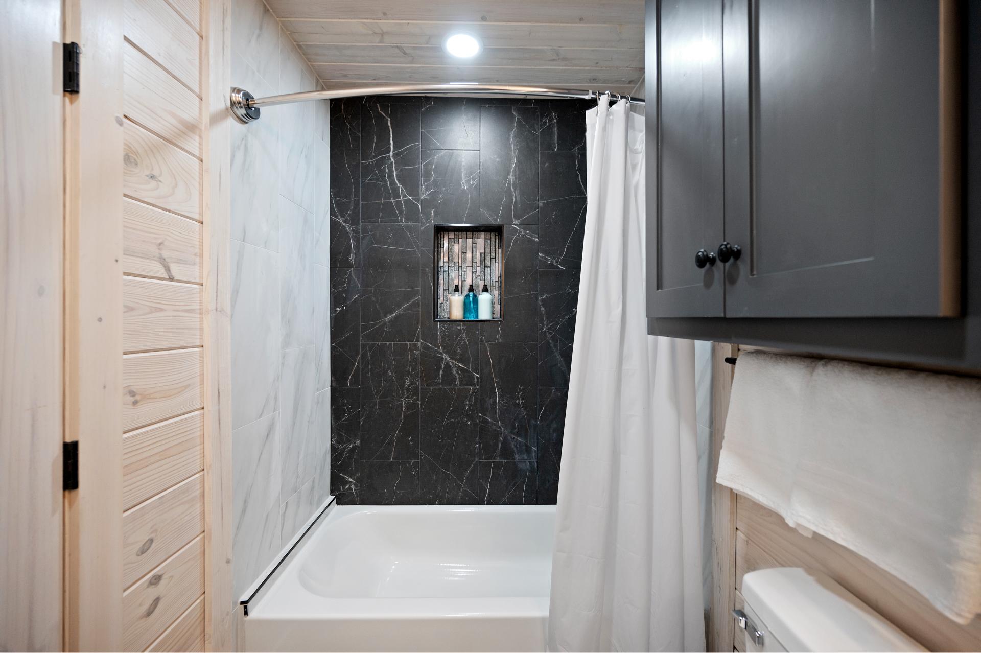 Wash away the day in this roomy tub and tiled shower—where comfort meets modern charm.
