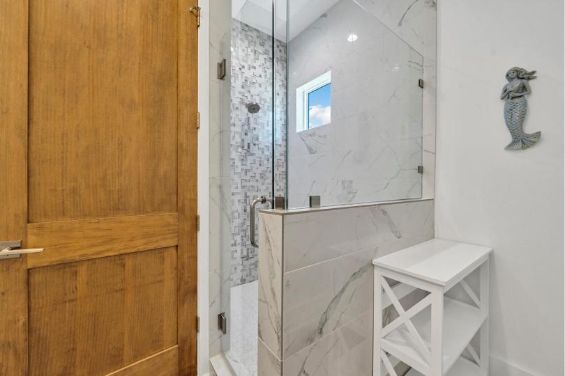 Main-floor Mermaid Bathroom features a sleek, tiled shower—perfect for a refreshing rinse after a beach day.