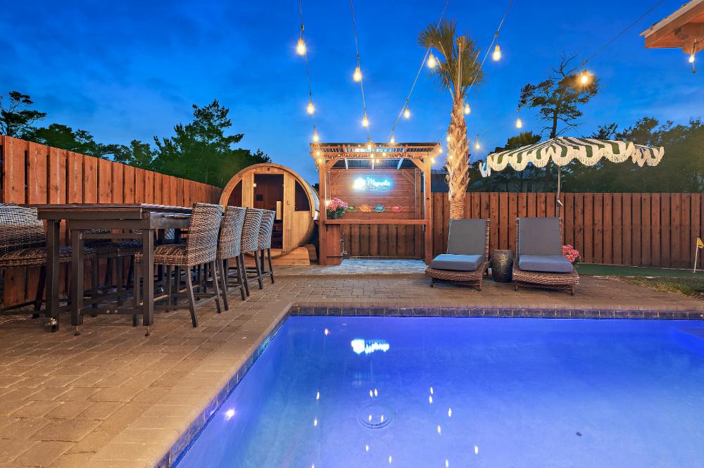Enjoy the private backyard oasis day or night! Pool can be heated, make your favorite drinks and snacks by the gazebo, enjoy a refresh in the barrel sauna, and compete in shuffleboard available under the outdoor dining table.