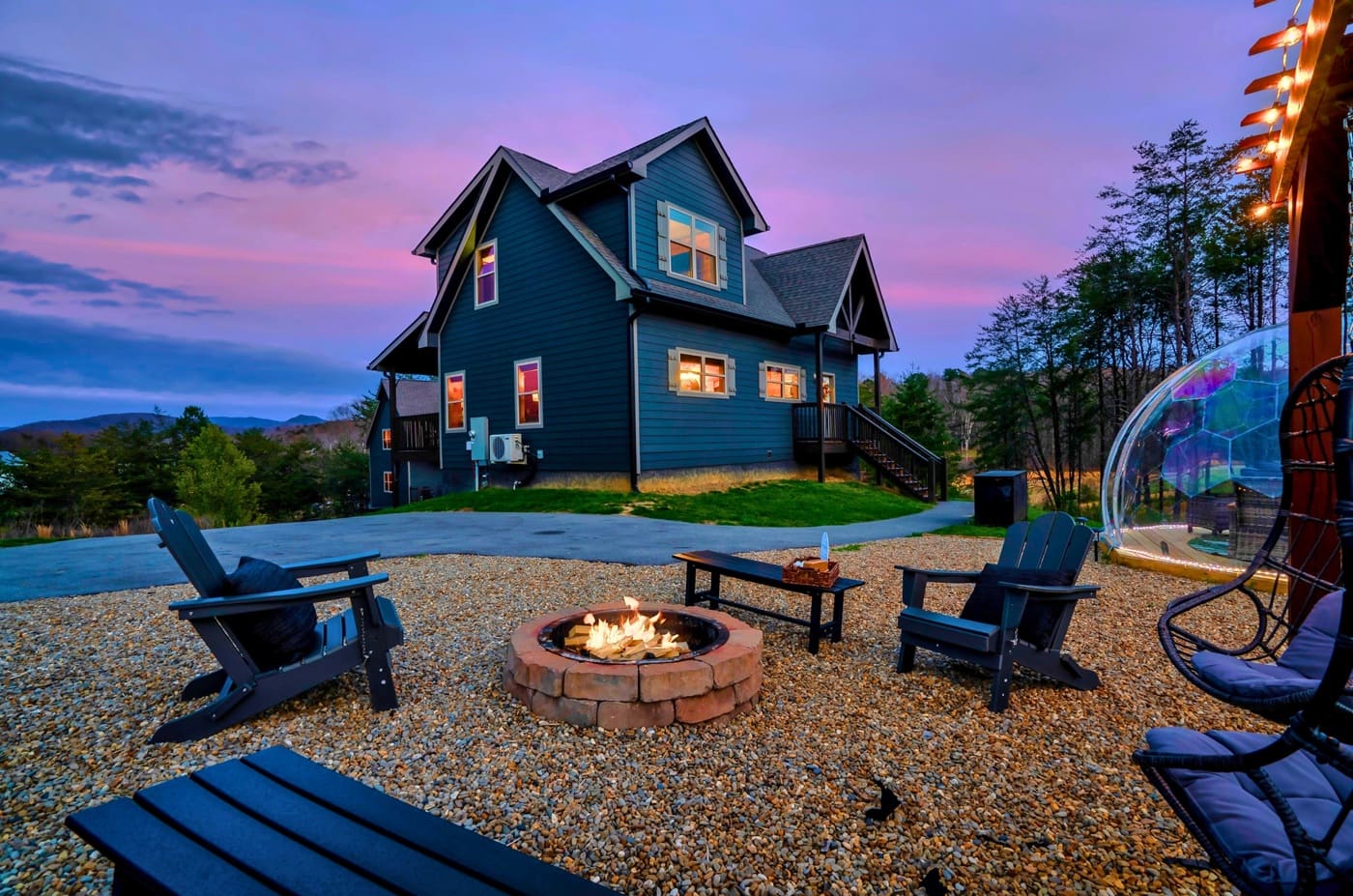 Fire pit area with Adirondack chairs and cabin views at sunset.