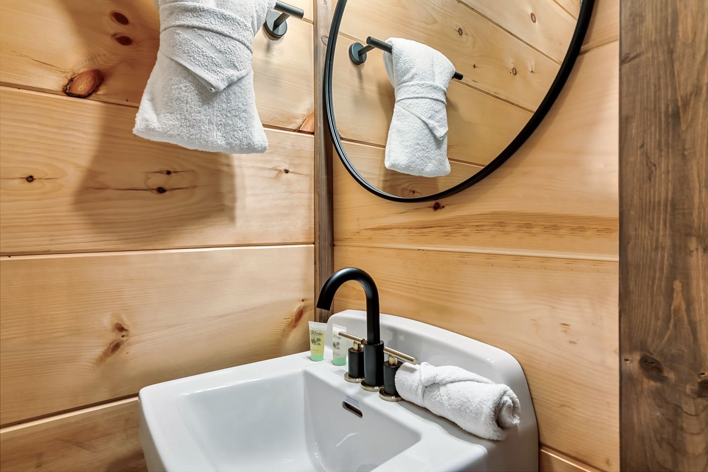 A clean and stylish bathroom setup with modern finishes and plush towels. This full bathroom is just off of the bunk room, game area, and indoor pool in the lower level.