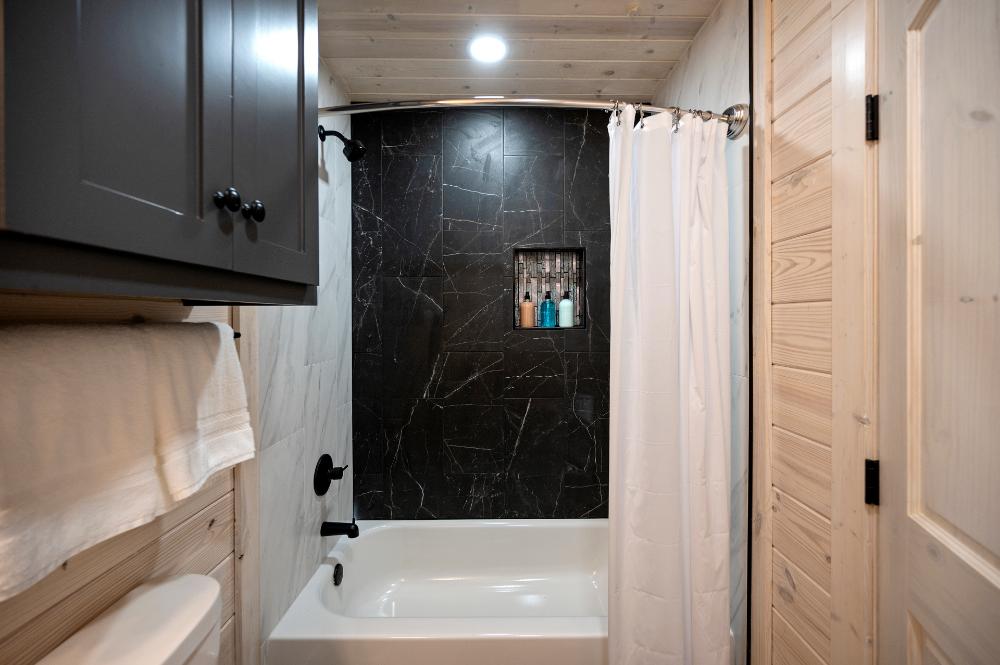 Bathroom with tiled finishes and tub and shower combination.