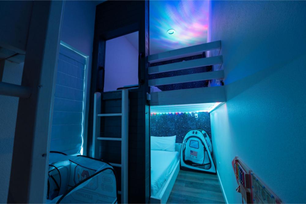 The Big Dipper-themed bunk room features twinkling star lights and four comfortable twin beds for a fun and cozy sleep space.