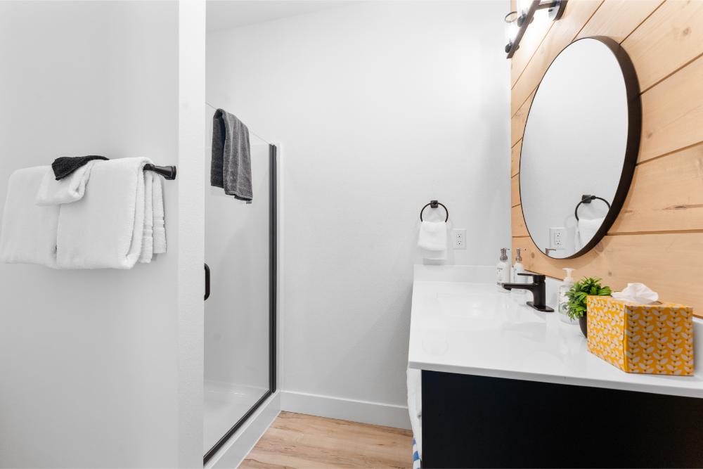 The ensuite bathroom features a glass-door shower and modern finishes for a relaxing experience.