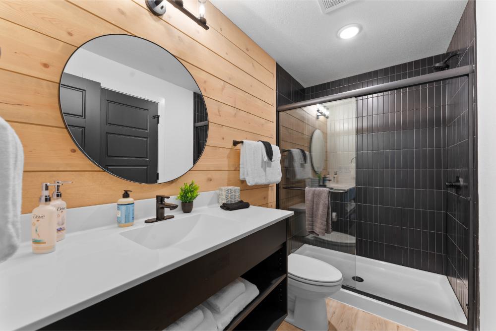Main-floor bathroom features sleek tile finishes and convenient shared access for guests.