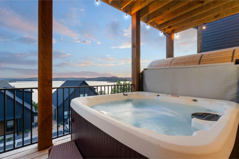 The lower-level deck offers a private hot tub, barrel sauna, and stunning panoramic lake views.
