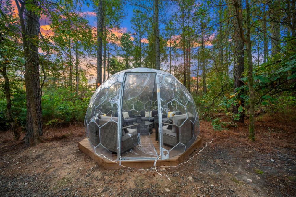 At twilight, the geodome transforms into a glowing retreat nestled among the trees.