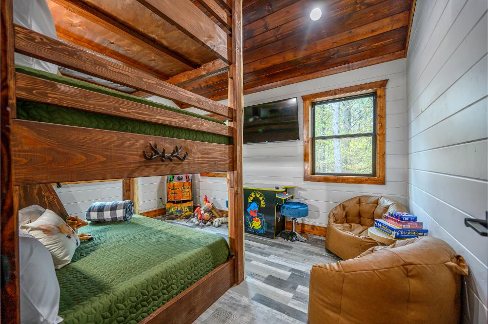 This bunk room is built for fun—comfy full-size bunks, old-school arcade games, and a Smart TV for the ultimate kids’ hangout. 