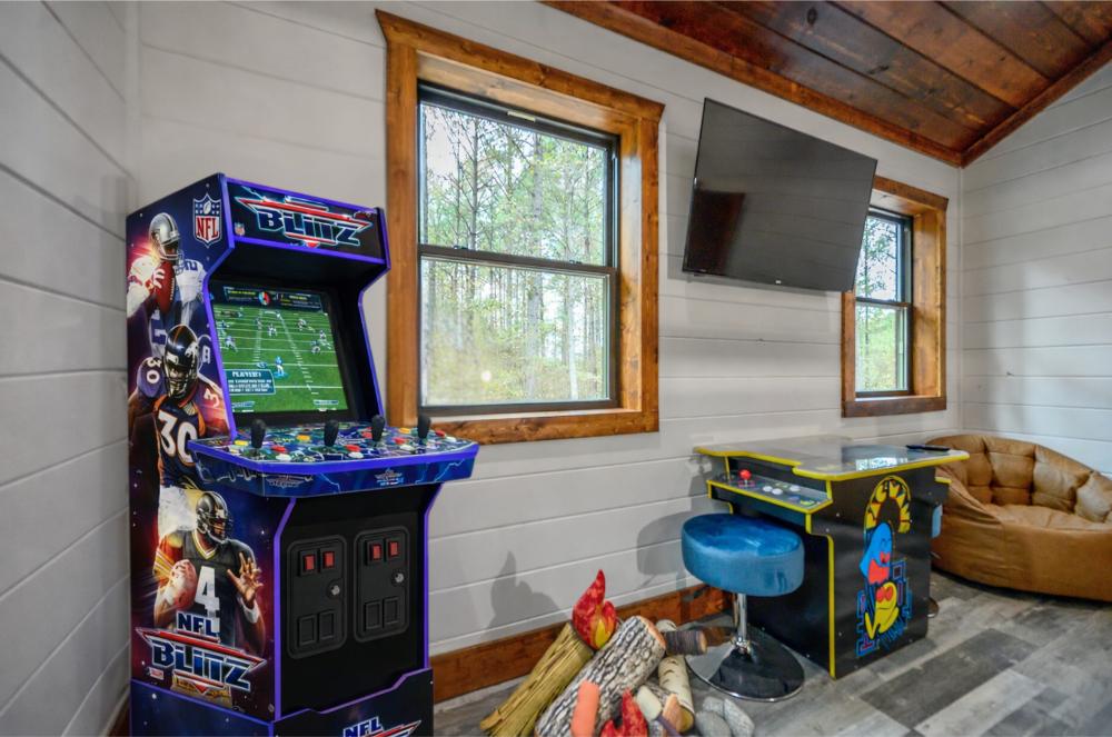 Entertainment-filled bunk room featuring a classic arcade machine, wall-mounted TV, and cozy lounge seating