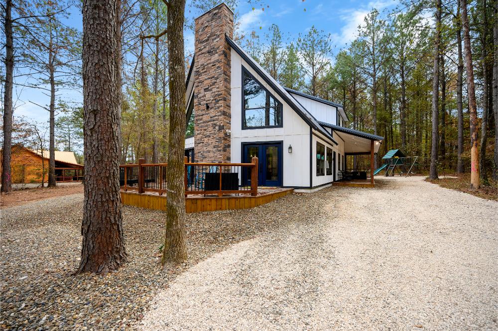 This charming cabin exterior offers a peaceful wooded setting with a spacious deck for relaxing outdoor living.