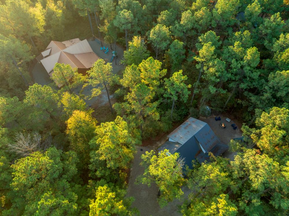 Aerial view of both neighboring cabins nestled among tall trees—offering a private, side-by-side setup for larger groups.