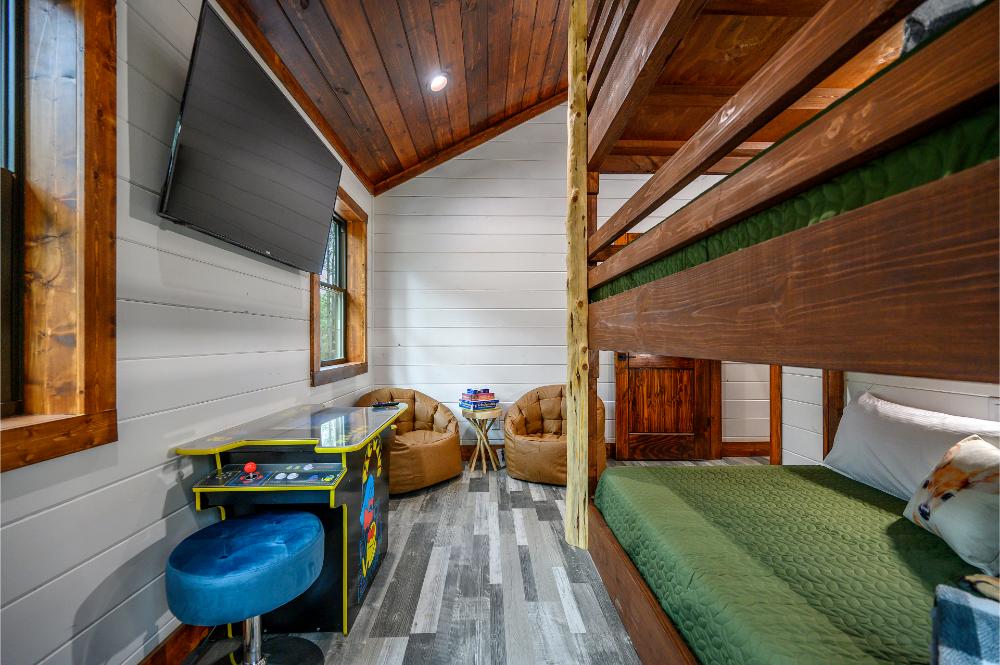 This bunk room includes three full-size bunks, arcade games, a Smart TV, and comfortable seating for kids and teens.